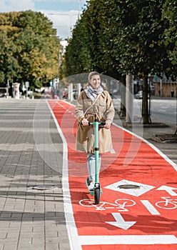 woman riding scooter along bike lane road in city