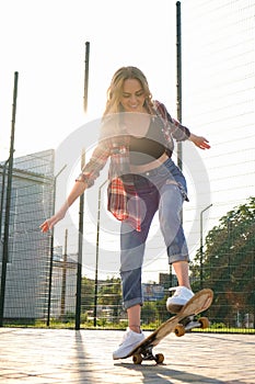 Woman riding a skateboard on street. Skater girl on a longboard. Cool female skateboarder at sunset. Carefree female