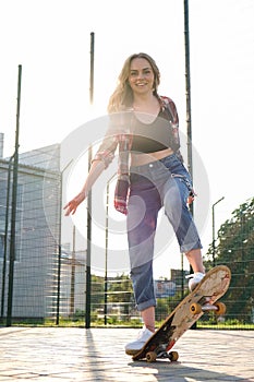 Woman riding a skateboard on street. Skater girl on a longboard. Cool female skateboarder at sunset. Carefree female