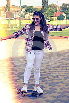 Woman riding a skateboard on street. Skater girl on a longboard. Cool female skateboarder at sunset. Carefree female