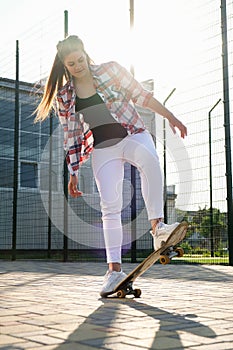 Woman riding a skateboard on street. Skater girl on a longboard. Cool female skateboarder at sunset. Carefree female