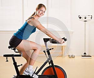 Woman riding stationary bicycle in health club