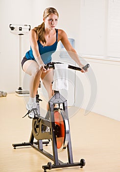 Woman riding stationary bicycle in health club