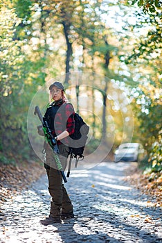 Woman with rifle in the forest. Car in the background