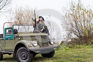 Woman with rifle posing on military car