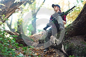 Woman with a rifle sitting on a log