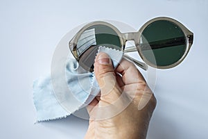 Woman right hand cleaning sunglasses by microfibre cleaning cloths, On white background, Close up & Macro shot, Optical concept