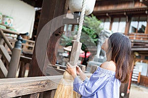 Woman ringing the bell in japanese temple