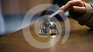 Woman ringing hotel service bell at reception desk, close up