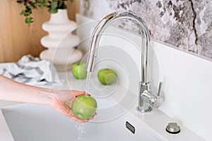 woman rinse fruit under chrome tap at stylish apartment