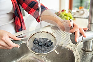 Woman rinses blueberries on the strainer photo