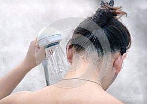 Woman Rinses Neck with a Hand Held Shower Head. photo