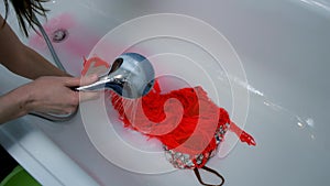 Woman is rinsing dress in bathroom under a stream of water by hands, closeup.