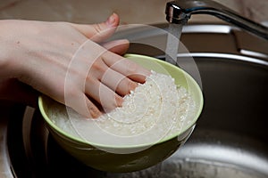 Woman rinsing rice in bowl under running water