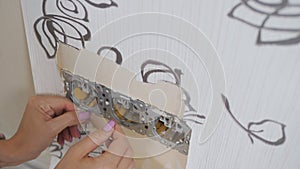 A woman rips the old Wallpaper off the wall to put on new ones, Close-up.