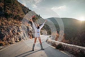 Woman road mountain. A woman in a white sweater, black boots and a hat walks along a winding alpine path between the