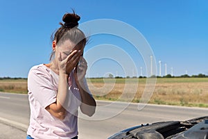 Woman on the roadside near broken car talking on cell phone