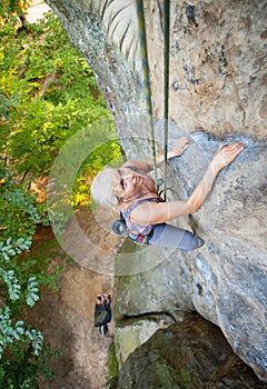 Woman rock climber is climbing on a rocky wall