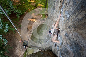 Woman rock climber is climbing on a rocky wall