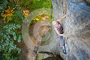 Woman rock climber is climbing on a rocky wall