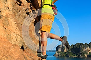 Woman rock climber climbing at seaside cliff