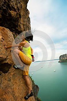 Woman rock climber climbing at seaside cliff