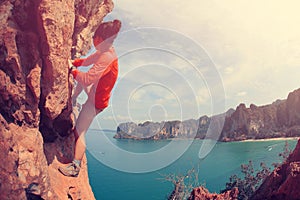 Woman rock climber climbing at seaside mountain cliff rock
