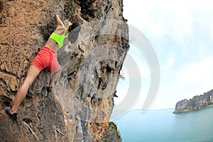 Woman rock climber climbing at seaside mountain cliff rock