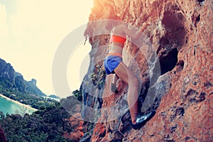 Woman rock climber climbing at seaside mountain cliff rock