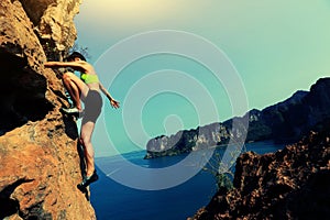 Woman rock climber climbing at seaside mountain rock