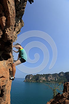 Woman rock climber climbing at seaside mountain rock