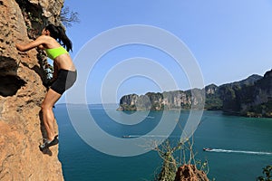 Woman rock climber climbing at seaside mountain rock