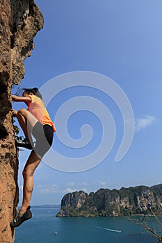 Woman rock climber climbing at seaside mountain rock