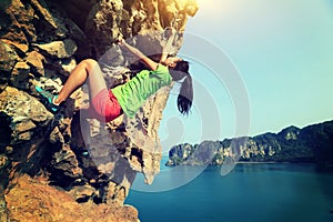 Woman rock climber climbing at seaside mountain rock