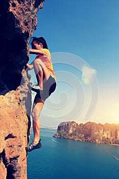 Woman rock climber climbing at seaside mountain rock