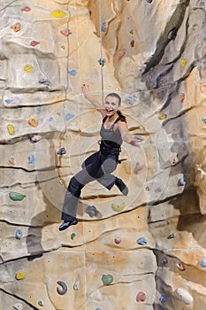 Woman on rock wall in sport centre