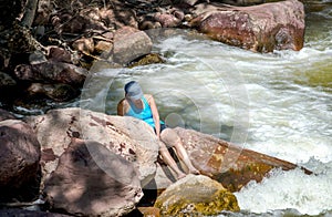 A woman on rocks near white water rapids in Colorado