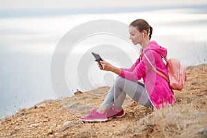 Woman on a rocky beach with a tablet in the spring