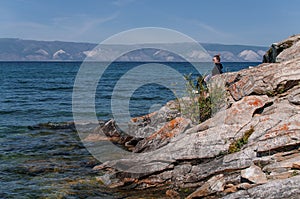 Woman on a rocky shore near the water of Lake Baikal