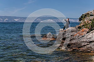 Woman on a rocky shore near the water of Lake Baikal