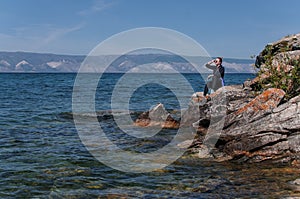 Woman on a rocky shore near the water of Lake Baikal