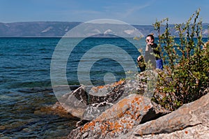 Woman on a rocky shore near the water of Lake Baikal