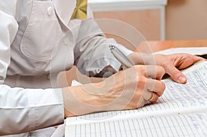 Woman-roentgenographer in polyclinic office writes patient data photo