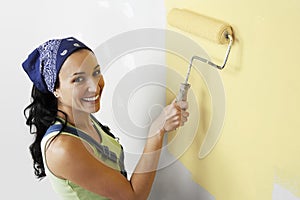Woman With Roller Applying Yellow Paint On A Wall