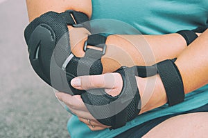 Woman rollerskater with elbow protector pads on her hand