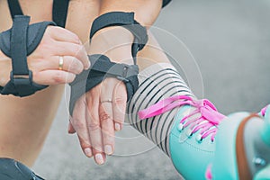 Woman rollerskater putting on wrist guards protector pads