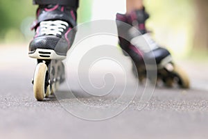 Woman is rolling on black beautiful rollerblades on asphalt closeup