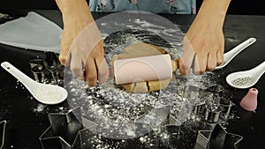 Woman is rolling out dough with little rolling pin. Female hands rolls raw dough for cookies using rolling pin. Process of making