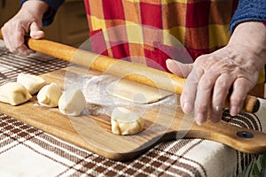 Woman rolling out the dough with a rolling pin on the kitchen table