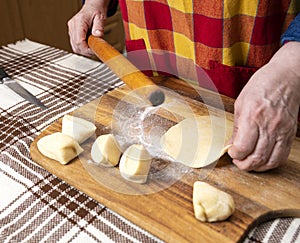 Woman rolling out the dough with a rolling pin on the kitchen table